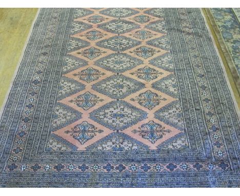 A BOOKHARA WOOL RUG the light pink and beige central panel with floral filled panels and serrated edge within an indigo eight
