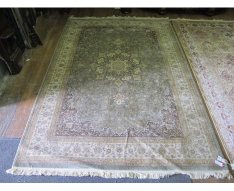 A WOOL RUG the light green and beige ground with central floral panel within a conforming border 238cm x 158cm