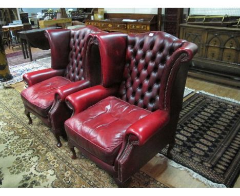 A PAIR OF WINE HIDE UPHOLSTERED WING LIBRARY CHAIRS each with a deep button upholstered back with scroll arms and loose cushi