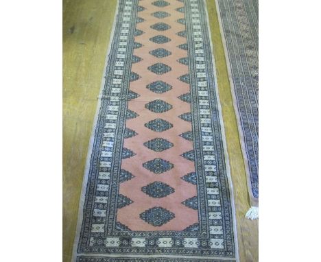 A BOOKHARA WOOL RUNNER the pink central panel with palmets within a conforming border 302cm long