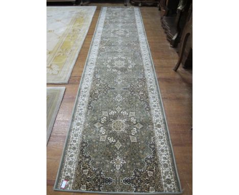 A WOOL RUNNER the light green and beige ground with central floral panel within a conforming border 426cm x 98cm