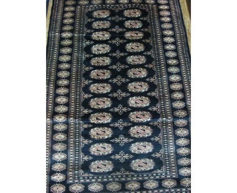 A WOOL RUG the indigo and light pink ground with central panels within a lattice work apron 154cm x 96cm