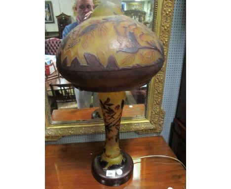 AN ETCHED GLASS TABLE LAMP with mushroom shade moulded in relief with flowerheads and foliage above a waisted column on circu