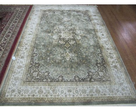 A WOOL RUG the light green and beige ground with central floral panel within a conforming border 237cm x 157cm