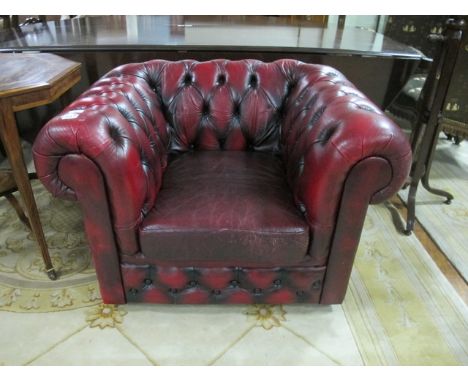 A WINE HIDE UPHOLSTERED LIBRARY CHAIR with deep button upholstered roll over back and arms with loose cushion on casters