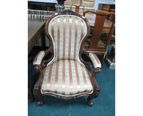 A VICTORIAN MAHOGANY GENTS CHAIR the carved top rail above an upholstered panel and seat with carved scroll arms on cabriole 