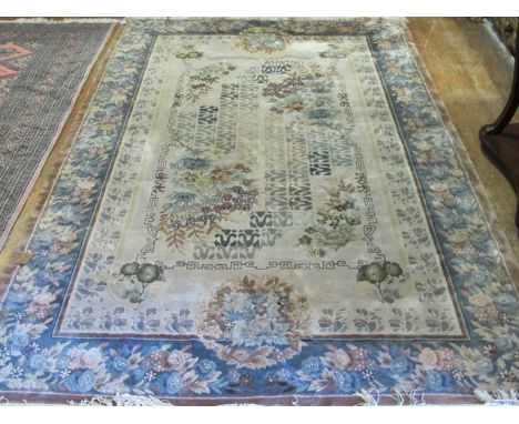 A CHINESE SILK RUG the beige ground with floral panels within a light blue border with flowerheads and foliage 277cm x 185cm