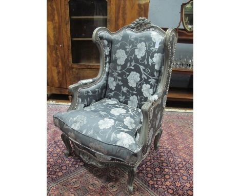 A PAIR OF CONTINENTAL SILVER AND PARCEL GILT WING CHAIRS each with a C scroll and flowerhead cresting above an upholstered ba