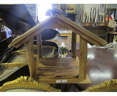 A RUSTIC GARDEN BIRD HOUSE the slatted pitched roof above an open shelf raised on a rustic base 154cm (h) x 64cm (w) x 48cm (