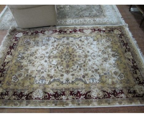 A WOOL RUG the beige ground with central floral panel within a wine floral border 203cm x 134cm