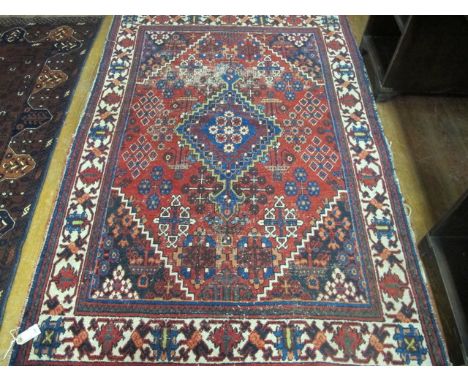 A PERSIAN WOOL RUG the wine, blue and beige ground with central serrated panel and stylized flowerheads within a three strand