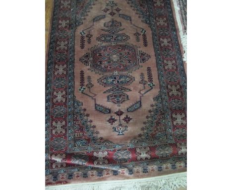 A PAKISTAN WOOL RUG the light pink and beige ground with central panel with palmets and stylized flowerheads within a four st