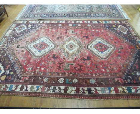 A PERSIAN WOOL RUG the pink and indigo ground with central diamond panel containing palmets and stylized flowerheads within a