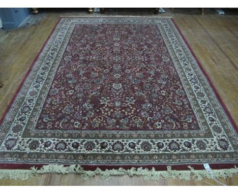 A WOOL RUG the wine and beige ground with central floral panel within a conforming border 287cm x 200cm