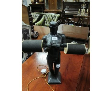 A FIGURAL TABLE LAMP modelled as a Gentleman shown standing holding a bar issuing two candle lamps 56cm high