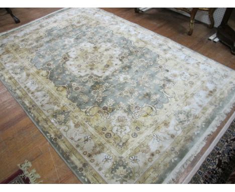 A WOOL RUG the green and beige ground with central floral panel within a beige border with flowerheads and foliage 286cm x 19