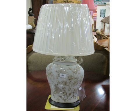 A PORCELAIN TABLE LAMP of ovoid form the light blue ground with floral decoration raised on an ebonised stand with pleated sh