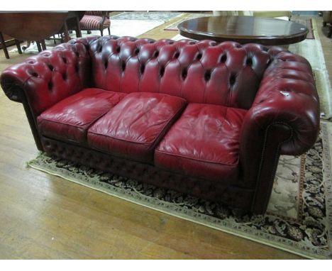 A WINE HIDE UPHOLSTERED LIBRARY COUCH with deep button upholstered back and seat with loose cushions 183cm wide