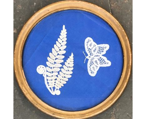 Two framed pieces of bobbin lace, fern and a butterfly mounted on a blue background, overall diameter 20cmD 