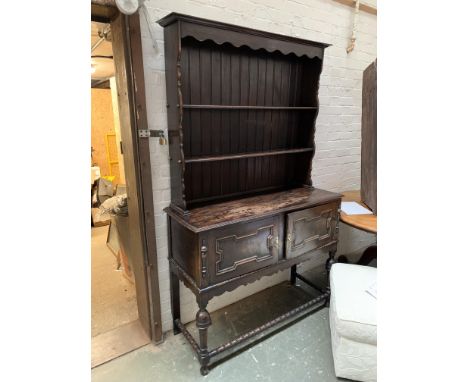An oak kitchen dresser, the top with two shelves, base with two drawers with geometric mouldings, on turned supports with bob