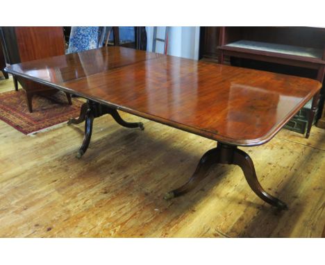 A Georgian mahogany twin pillar dining table, the top with rounded corners raised on ring turned and bulbous columns on swept