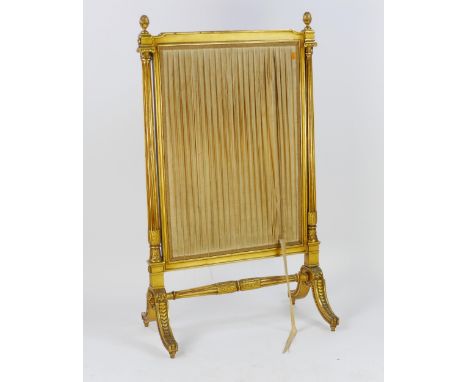 A gilt wood firescreen of rectangular outline, with silk work panel within fluted columns with pineapple finials, raised on s