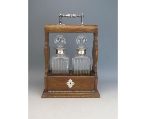 An Elizabeth II oak and silver mounted tantalus, by Carrs of London, containing two clear glass and silver mounted decanters 