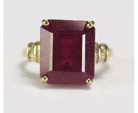 A large emerald cut ruby and diamond set ring in an unmarked yellow metal mount, size K. overall weight 4.2gms