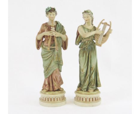 A pair of Royal Dux style neoclassical musicians, the female with a harp the male with twin pipes, 28cm high.