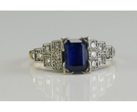 An Art Deco Style 18ct Gold, Diamond and Gem Set Ring, the central 6.86x4.83mm central stone shouldered by four step platinum
