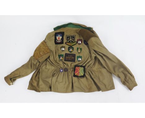 A cotton shooting jacket with applied cloth shooting badges, enamel badges, and two loose shooting medals.
