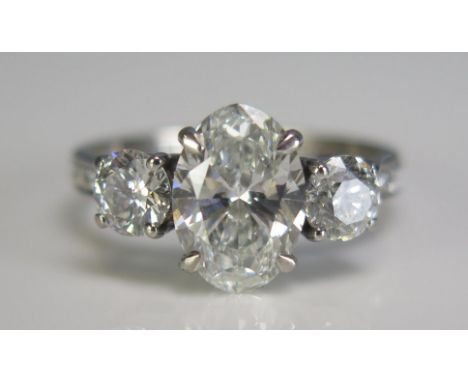 An 18ct white gold three stone diamond ring, the central 2ct laboratory grown diamond flanked by two natural diamonds approx 