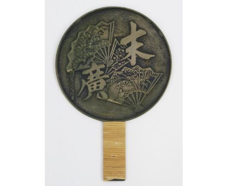 A Chinese bronze hand mirror, decorated with fan and characters and cane bound handle.