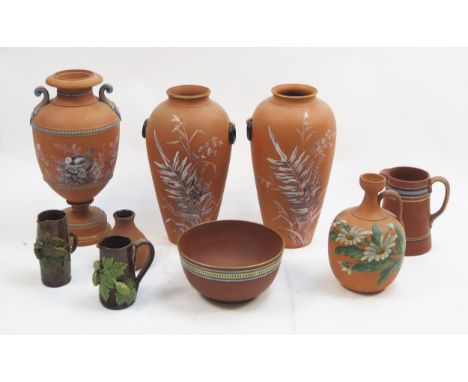 A collection of Torquay terracotta cases with painted floral and bird nest decoration, various sizes, including a bowl and ju