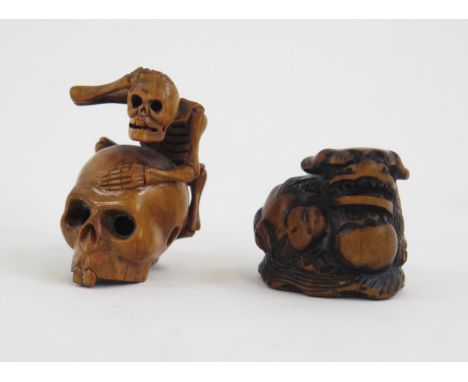 A Carved boxwood netsuke in the form of a skeleton climbing on a skull, signed, 5cm high, together with another netsuke of a 