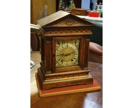 An oak cased German chiming mantle clock, the brass face with silvered chapter ring, retailed by Barraclough and Sons