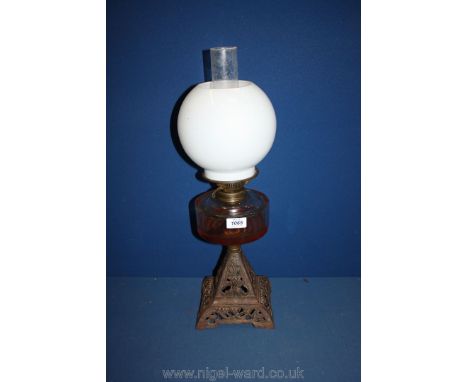An oil Lamp with a square open work base, glass reservoir and white glass shade.