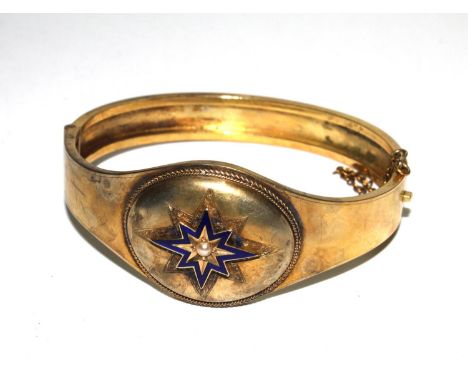 A gold colour metal bangle, decorated with blue enamel and a pearl set star 