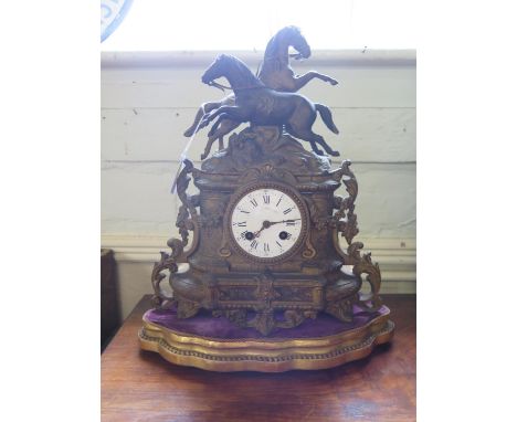 A French 19th century gilt spelter mantel clock, the two prancing horses over an enamelled dial and floral garlands, on a gil