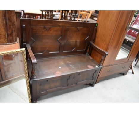A traditional oak monks bench having cushioned style panels, width approx. 115cm