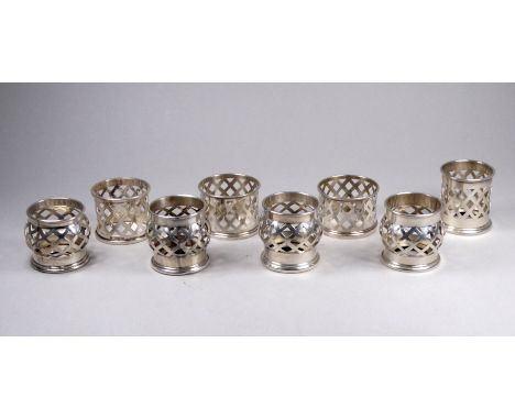 Four barrel shaped white metal tea light holders - with pierced geometric decoration, together with four similar serviette ri