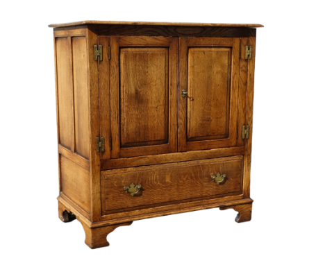 An oak cabinet - the pair of fielded panel doors enclosing a void interior above a drawer on shaped bracket feet, width 91cm,