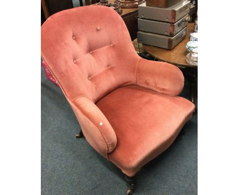 A pink upholstered button back armchair.