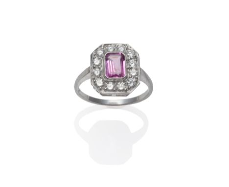 A Pink Sapphire and Diamond Cluster Ring, an emerald-cut pink sapphire within a border of round brilliant cut diamonds, in wh