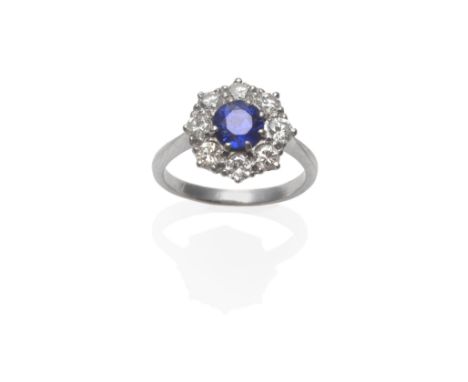 A Sapphire and Diamond Cluster Ring, the round mixed cut sapphire within a border of eight round brilliant cut diamonds in wh