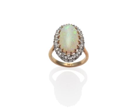 An Opal and Diamond Ring, the oval cabochon opal within a border of round brilliant cut diamonds, in yellow and white claw se