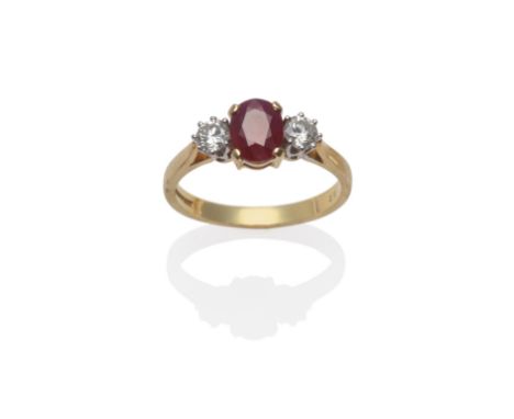 An 18 Carat Gold Ruby and Diamond Three Stone Ring, the oval mixed cut ruby flanked by a round brilliant cut diamond on each 