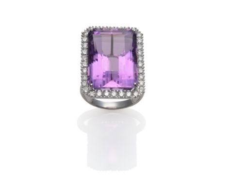 An 18 Carat White Gold Amethyst and Diamond Cluster Ring, the emerald-cut amethyst within a border of round brilliant cut dia