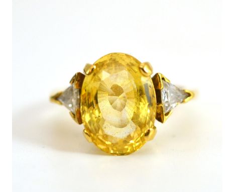 An 18 Carat Gold Yellow Sapphire and Diamond Three Stone Ring, the oval cut light yellow sapphire with a trillion cut diamond