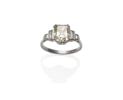 A Diamond Ring, circa 1920, the emerald-cut central diamond in a white split claw setting, with a pair of graduated baguette 